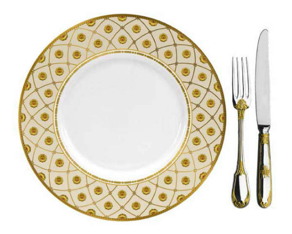 A gold and white dinner plate with a knife and fork